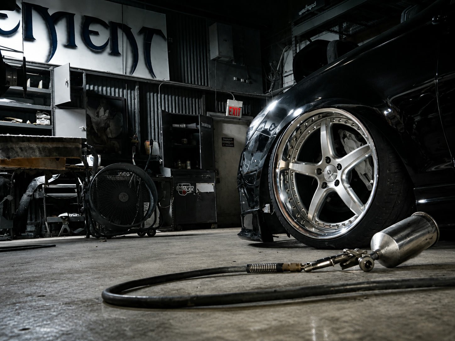 A polished wheel on a black car inside the Solo Element shop at night