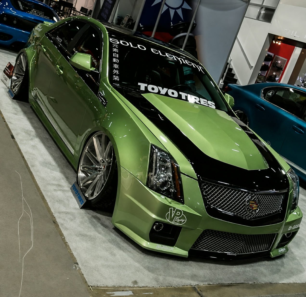 Green wide-body Cadillac CTS-V lowered on polished wheels