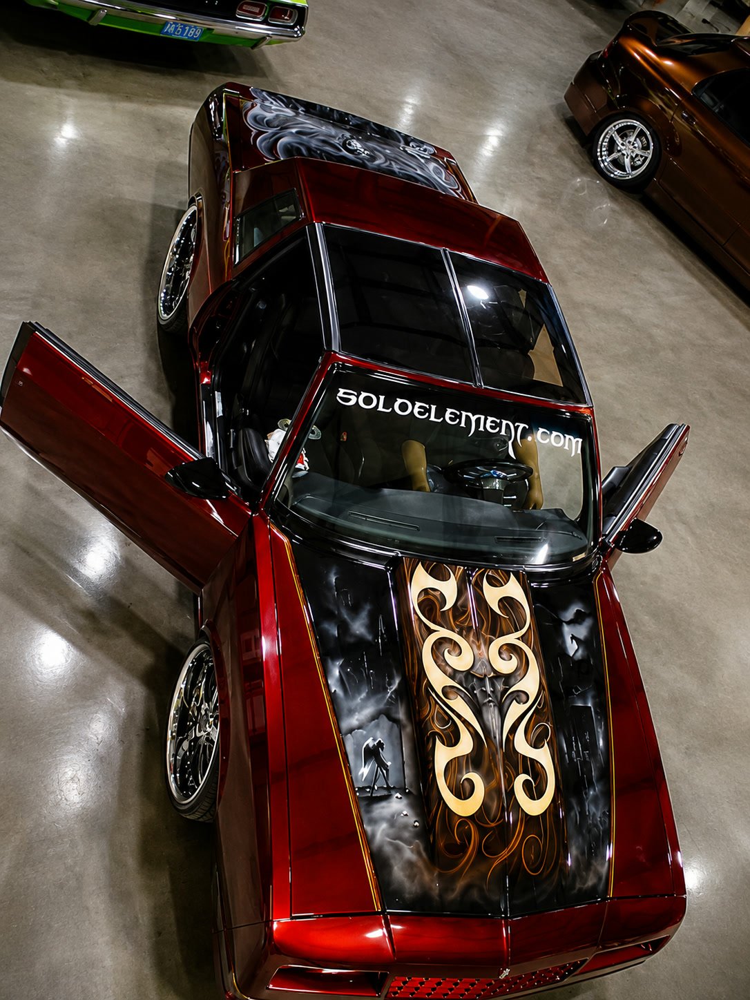 Candy red custom Chevrolet with airbrushed hood and gold pinstriping, doors open