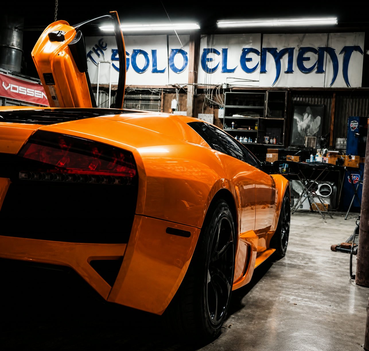 Orange Lamborghini Murcielago with a door raised inside the Solo Element shop